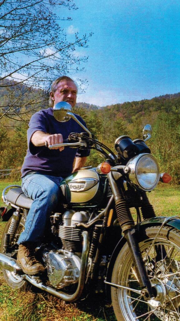 A modern photo of an older man sitting astride a motorcycle