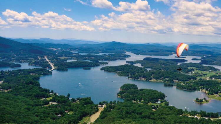 An aerial view of a lake with a paraplane in the foreground