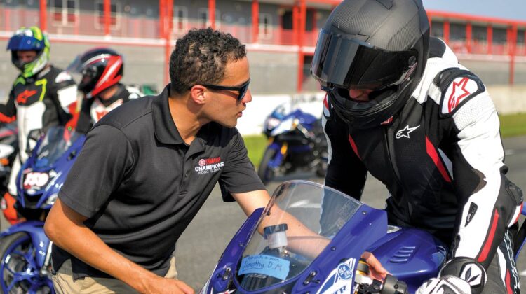 An instructor talks with a student on a motorcycle