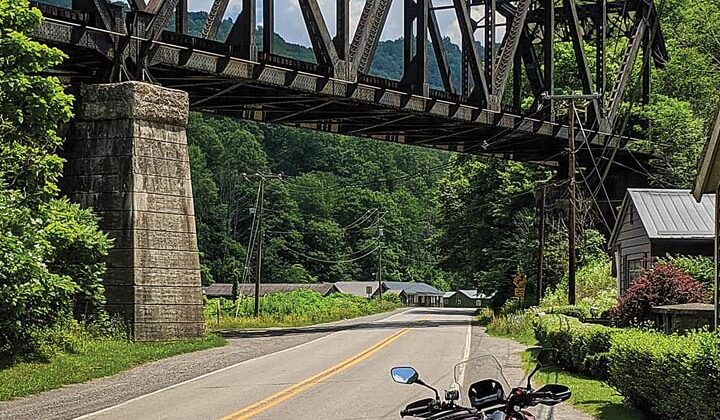 A motorcycle is in the foreground with a railroad trestle in the background