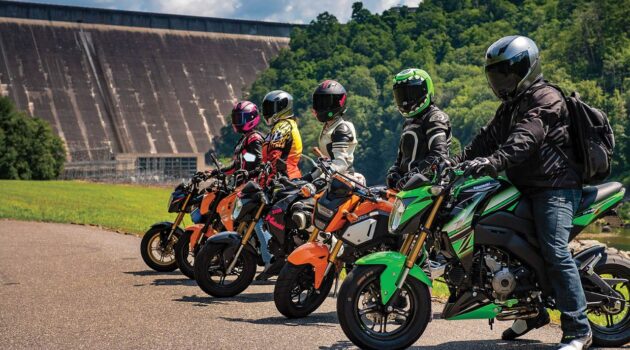 A group of motorcycle riders is parked in front of a dam