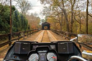 View over the dashboard of a motorcycle looking ahead to the opening of a covered bridge.