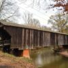 Side view of a covered bridge over a peaceful stream.