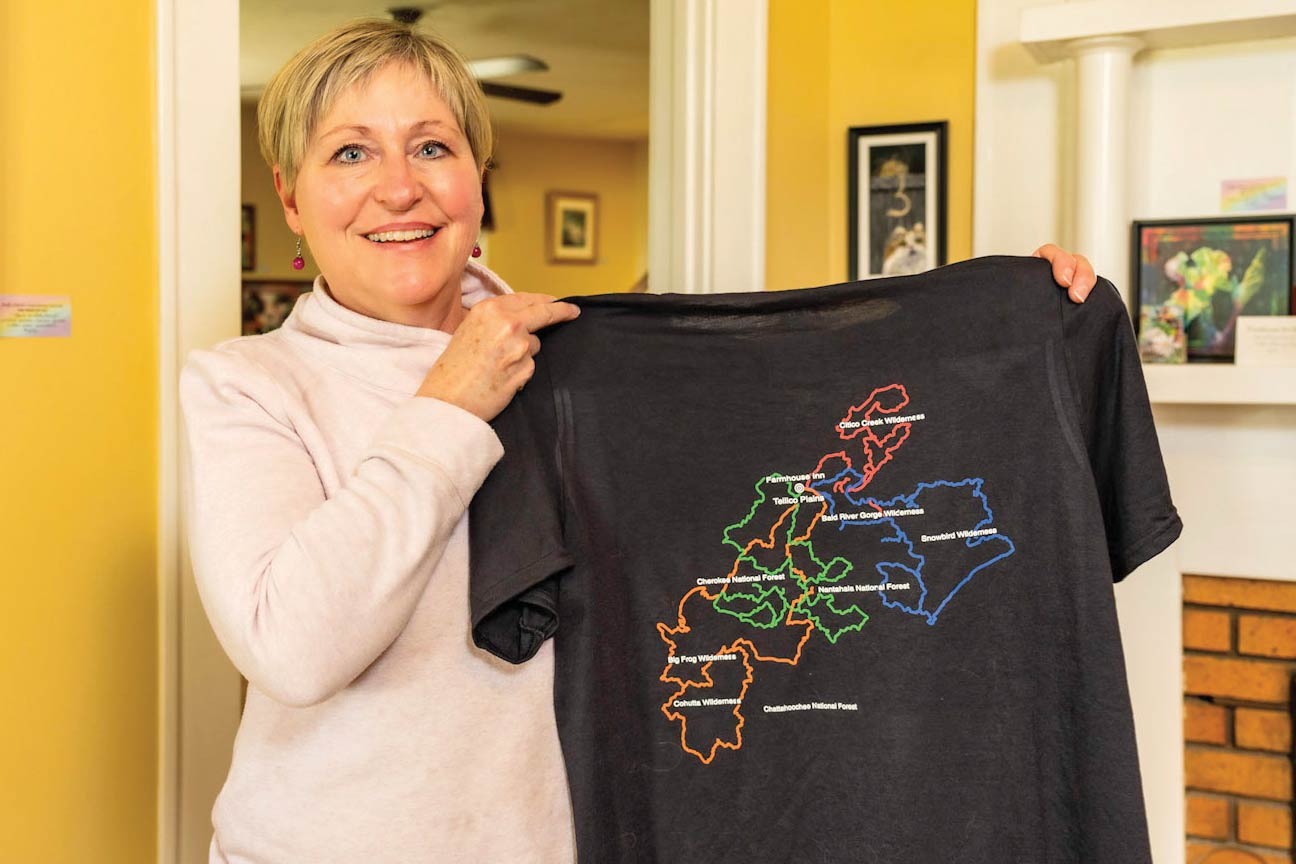 A woman displays a t-shirt that has a map printed on the back