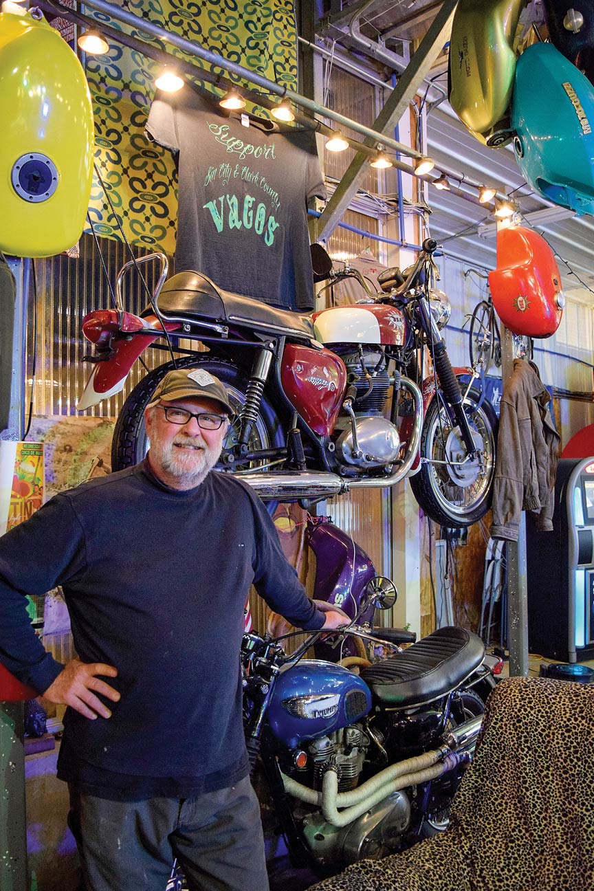A man stands beside some of his motorcycle collection