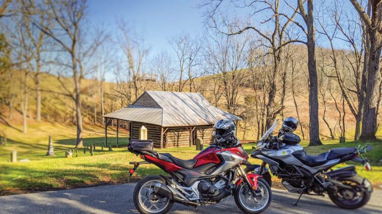 Two motorcycles are parked by a historic church. A graveyard is in the background.