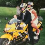 Newlyweds sit atop a yellow Honda motorcycle
