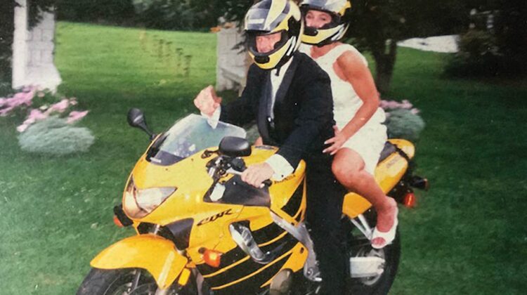 Newlyweds sit atop a yellow Honda motorcycle