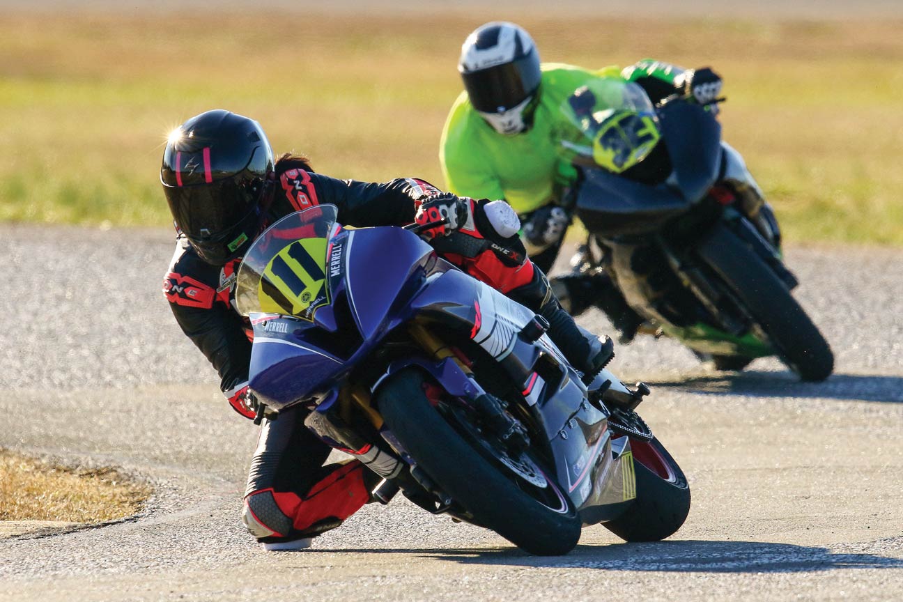Two motorcycle riders lean into a curve during a track event.