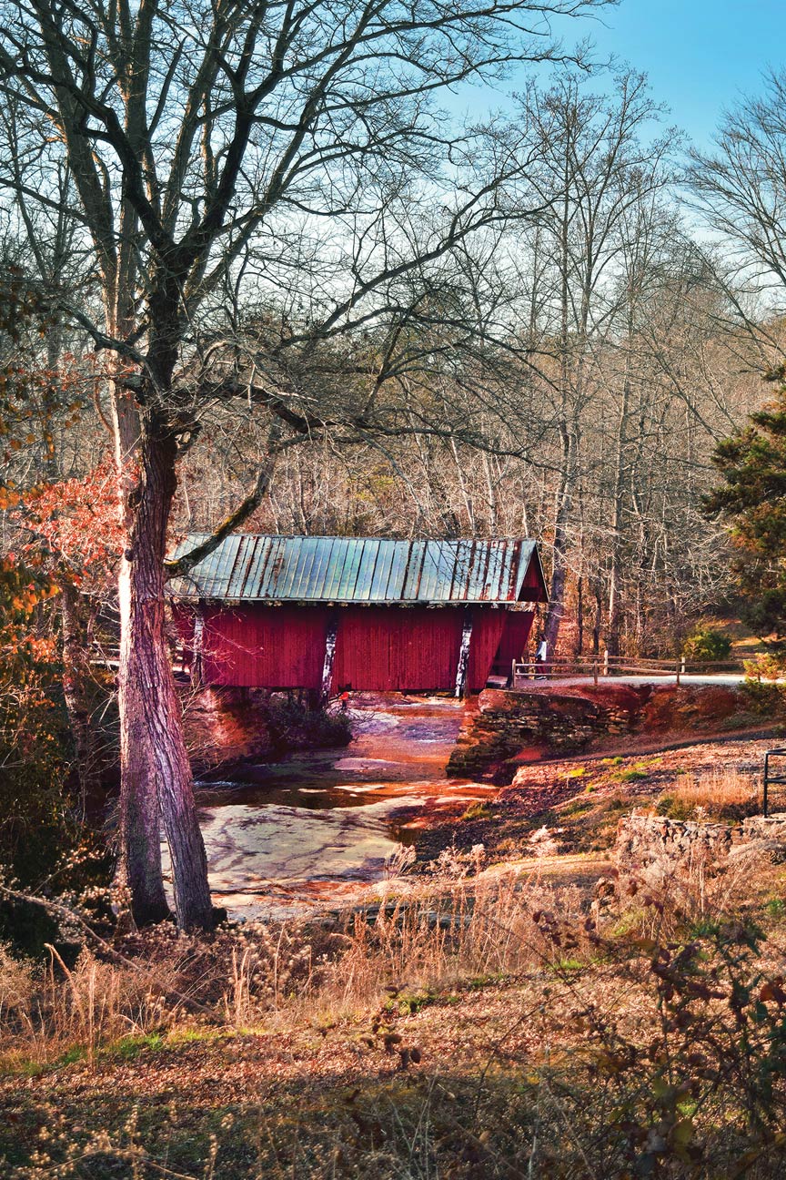 a distant view of a covered bridge in autumn