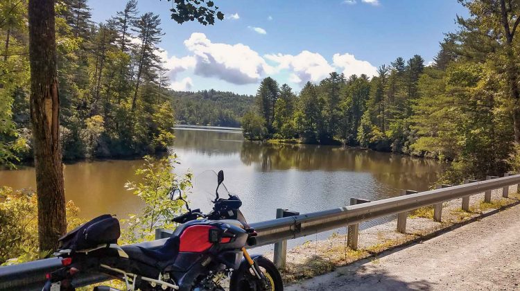 A motorcycle is parked beside a guardrail overlooking a lake