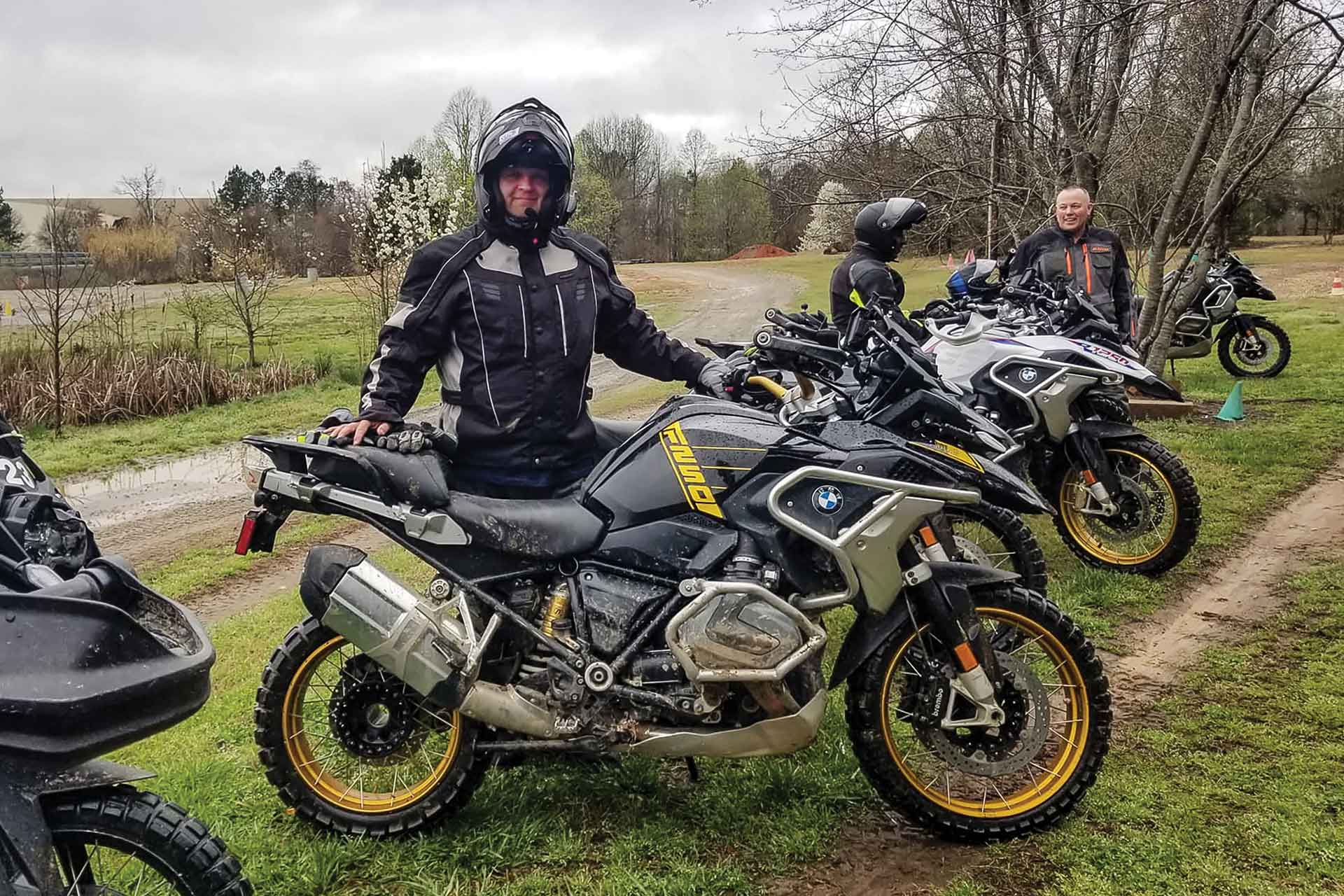 A group of riders stands with their motorcycles.