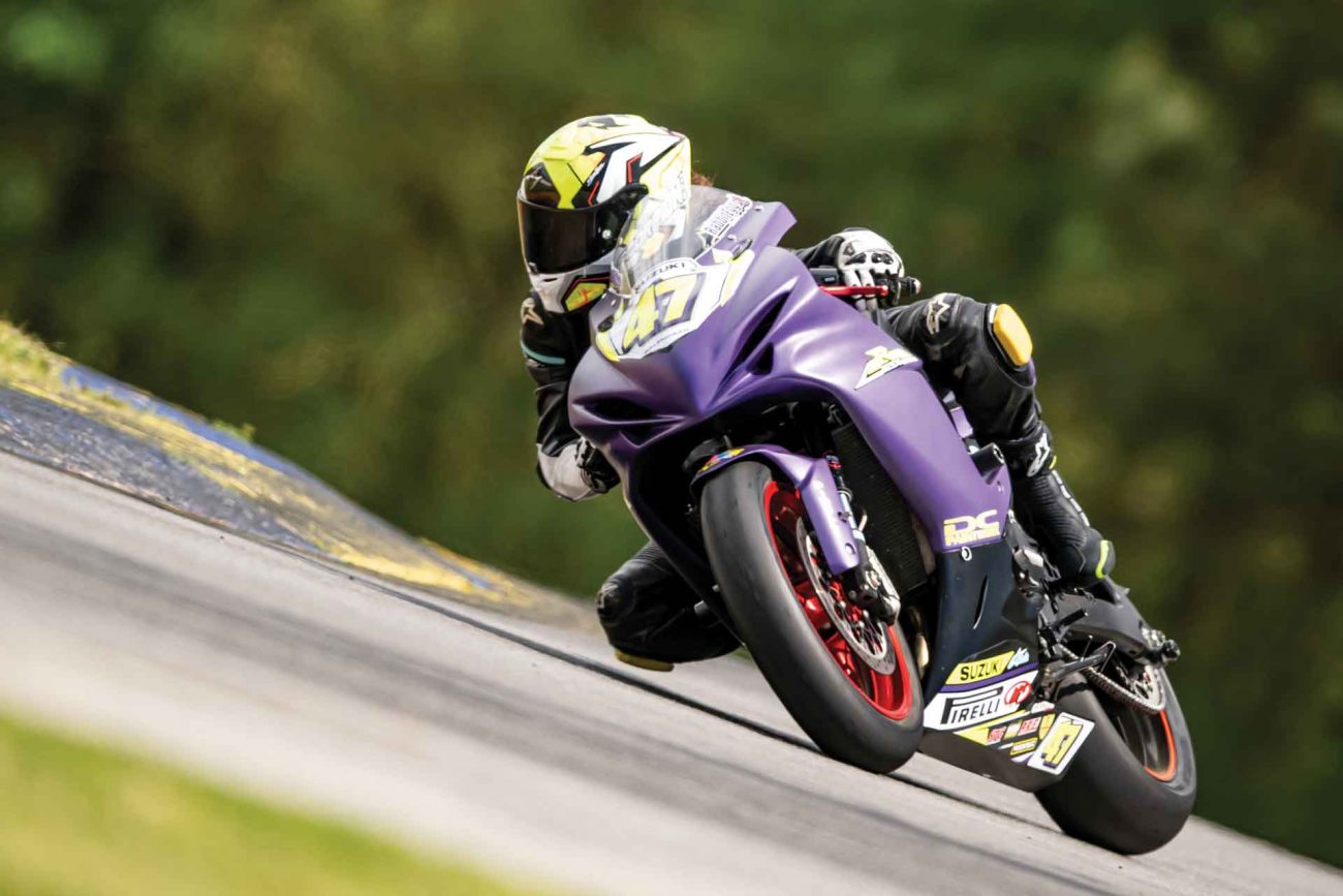 A rider on a purple Suzuki does a lap during a track day event.