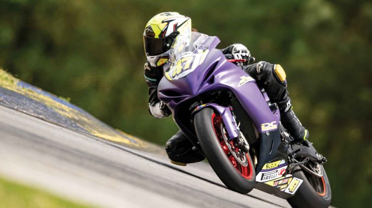 A rider on a purple Suzuki does a lap during a track day event.