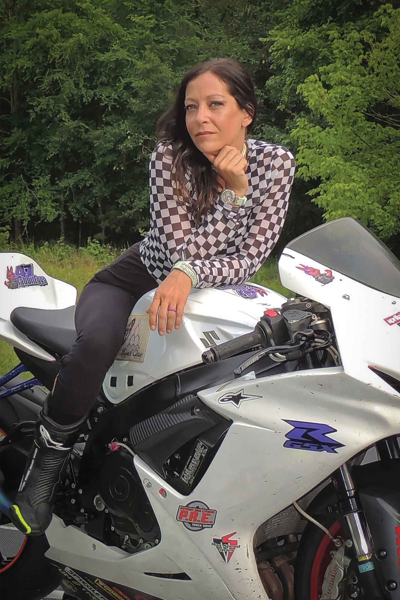 Janelle sits on a white Suzuki motorcycle