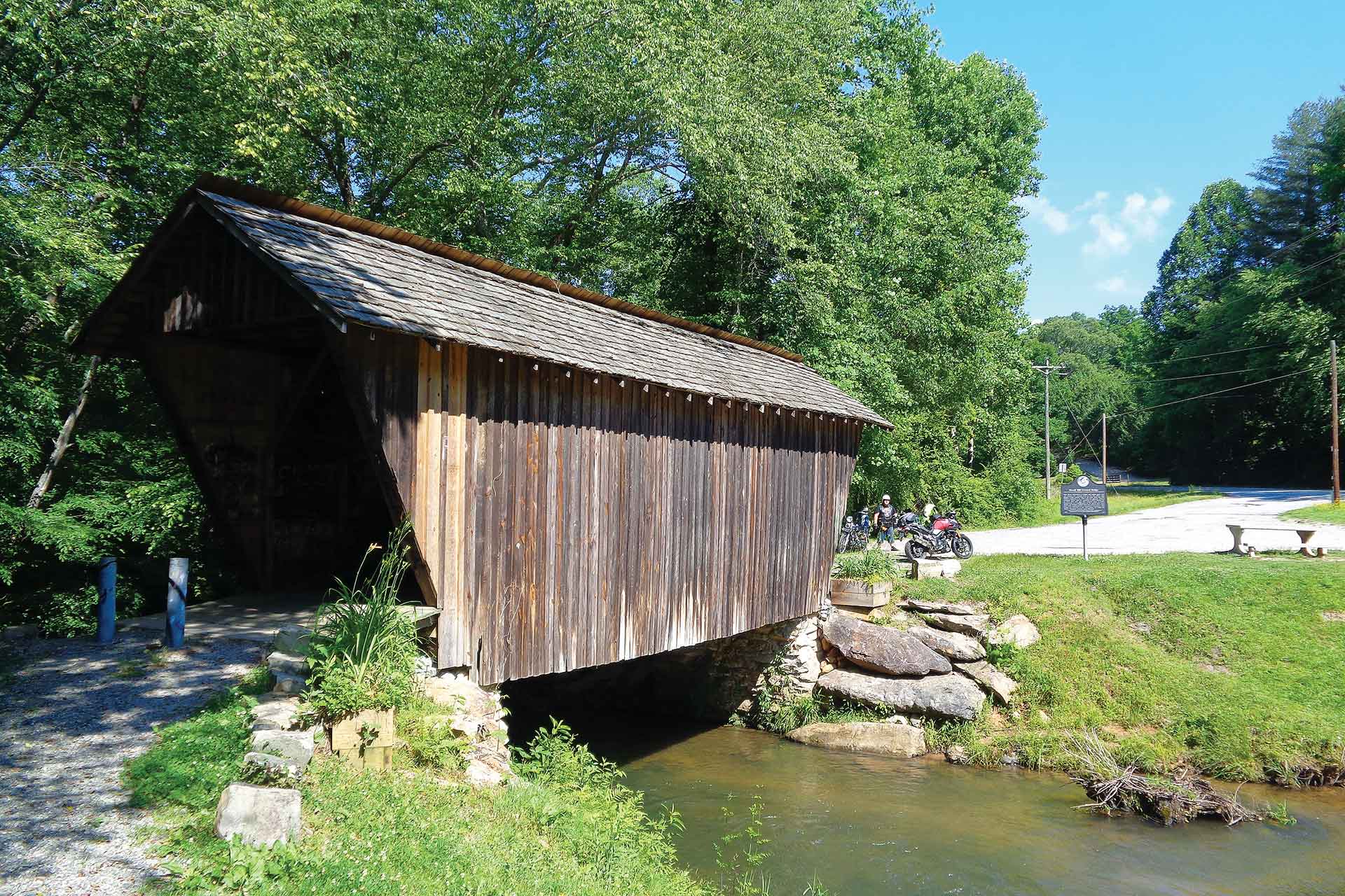 Motorcyclists take a break at a covered bridge.
