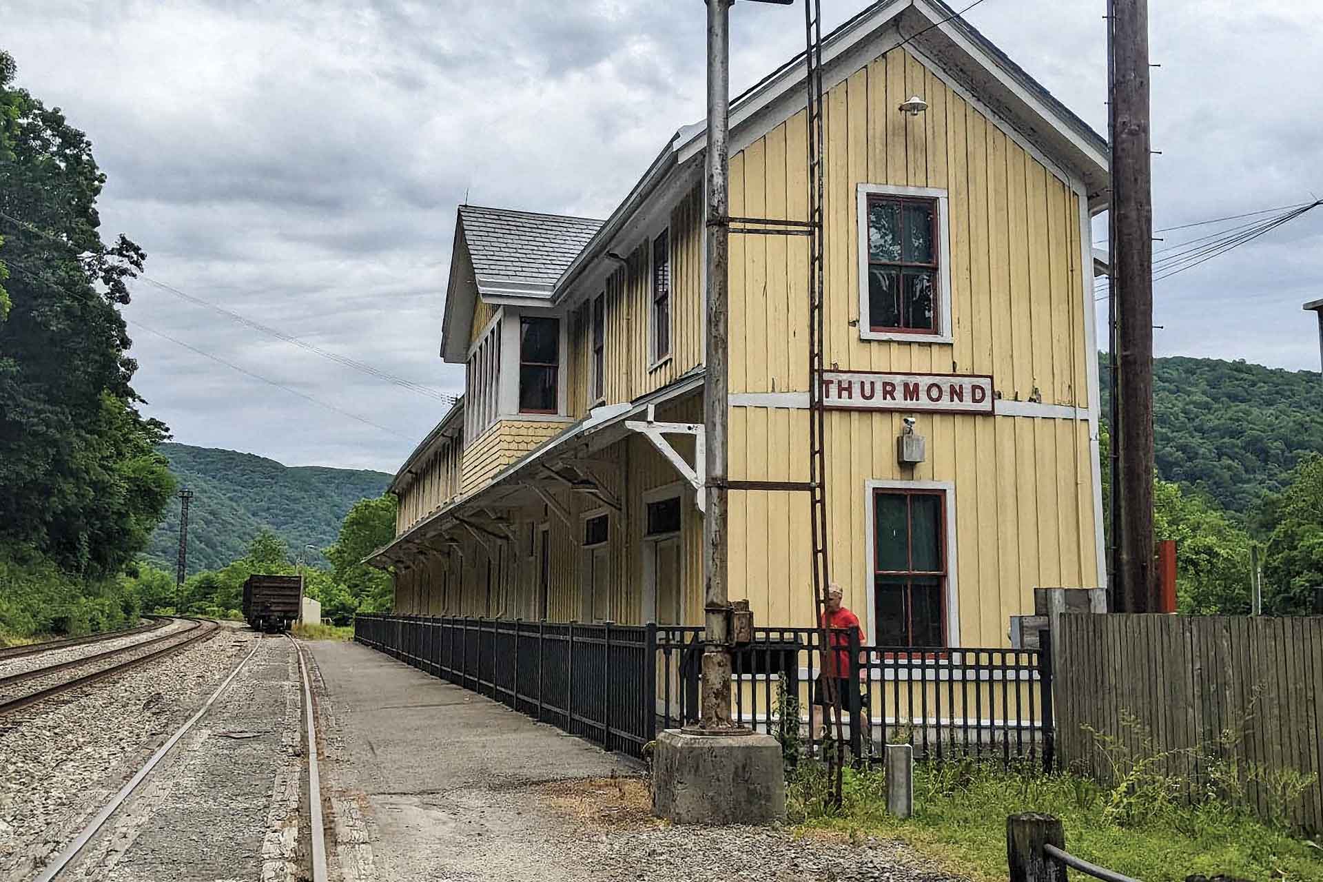 A yellow depot building stands beside an empty railroad track.