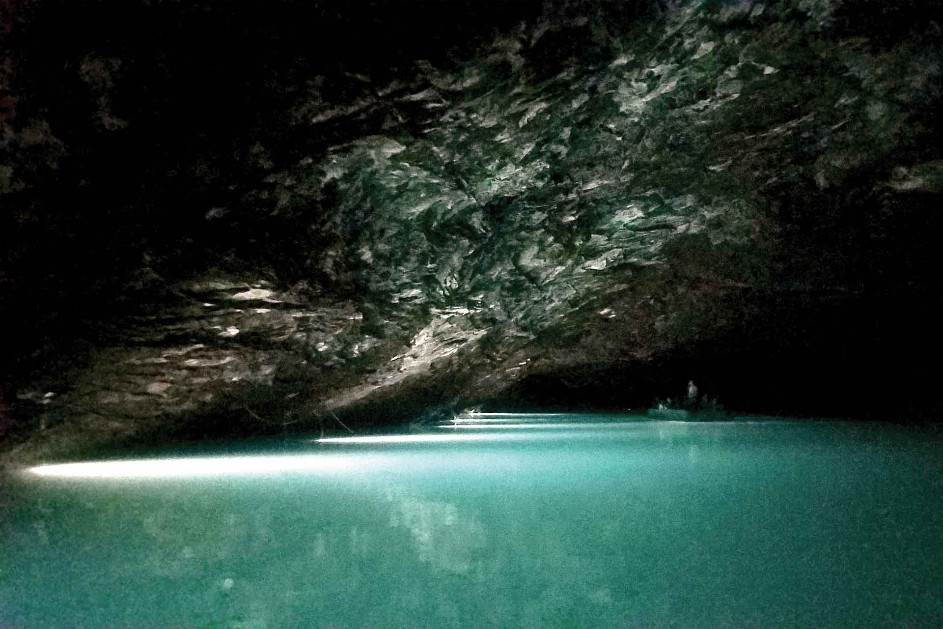 A view of an underground lake with a boat floating by.