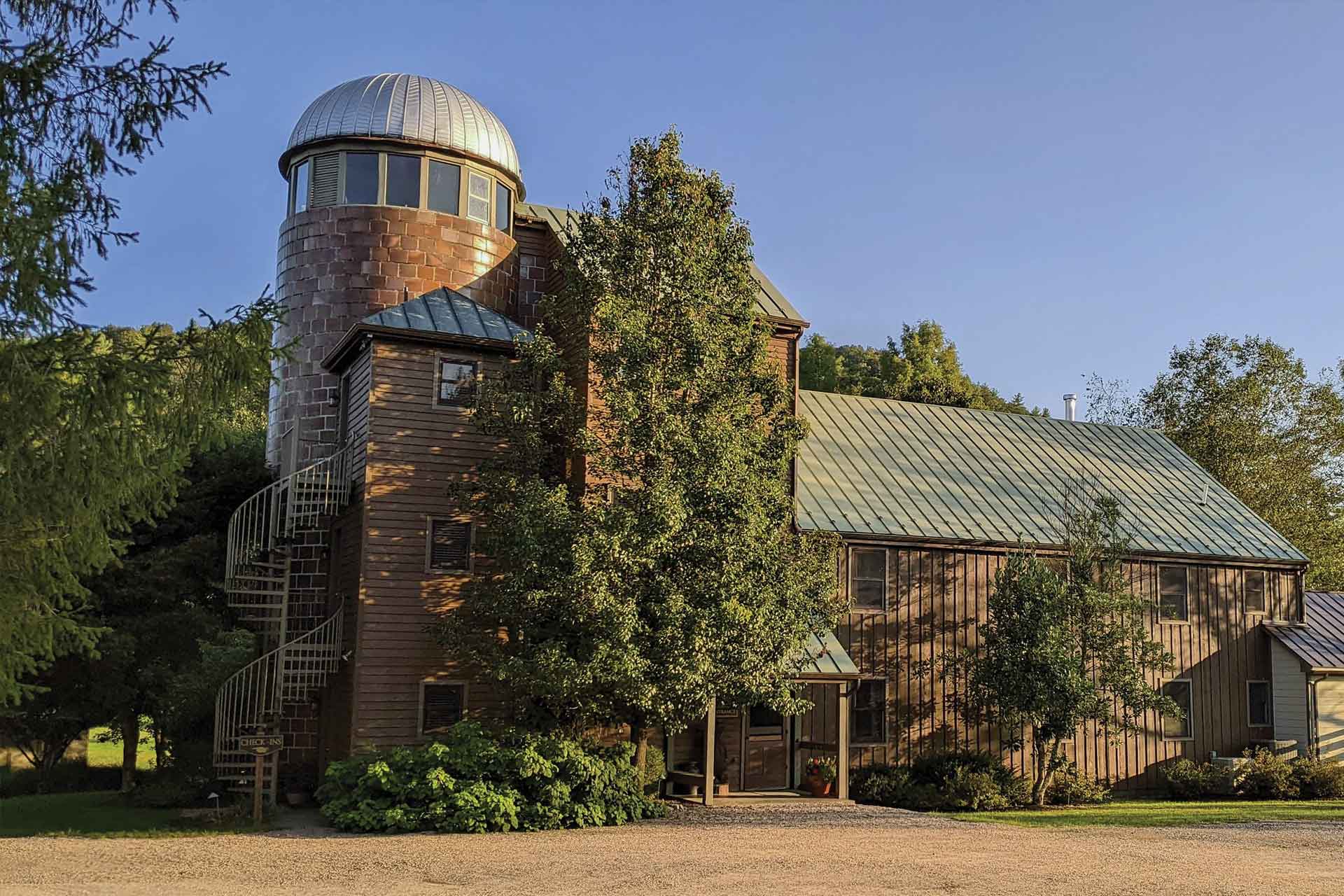 A rustic brown barn with a tall silo