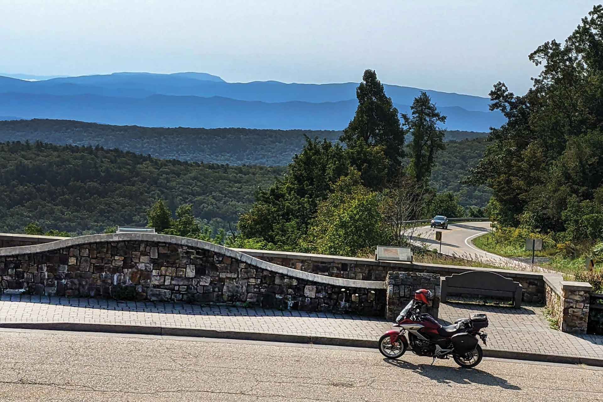 A red and silver motorcycle is parked at a scenic overlook