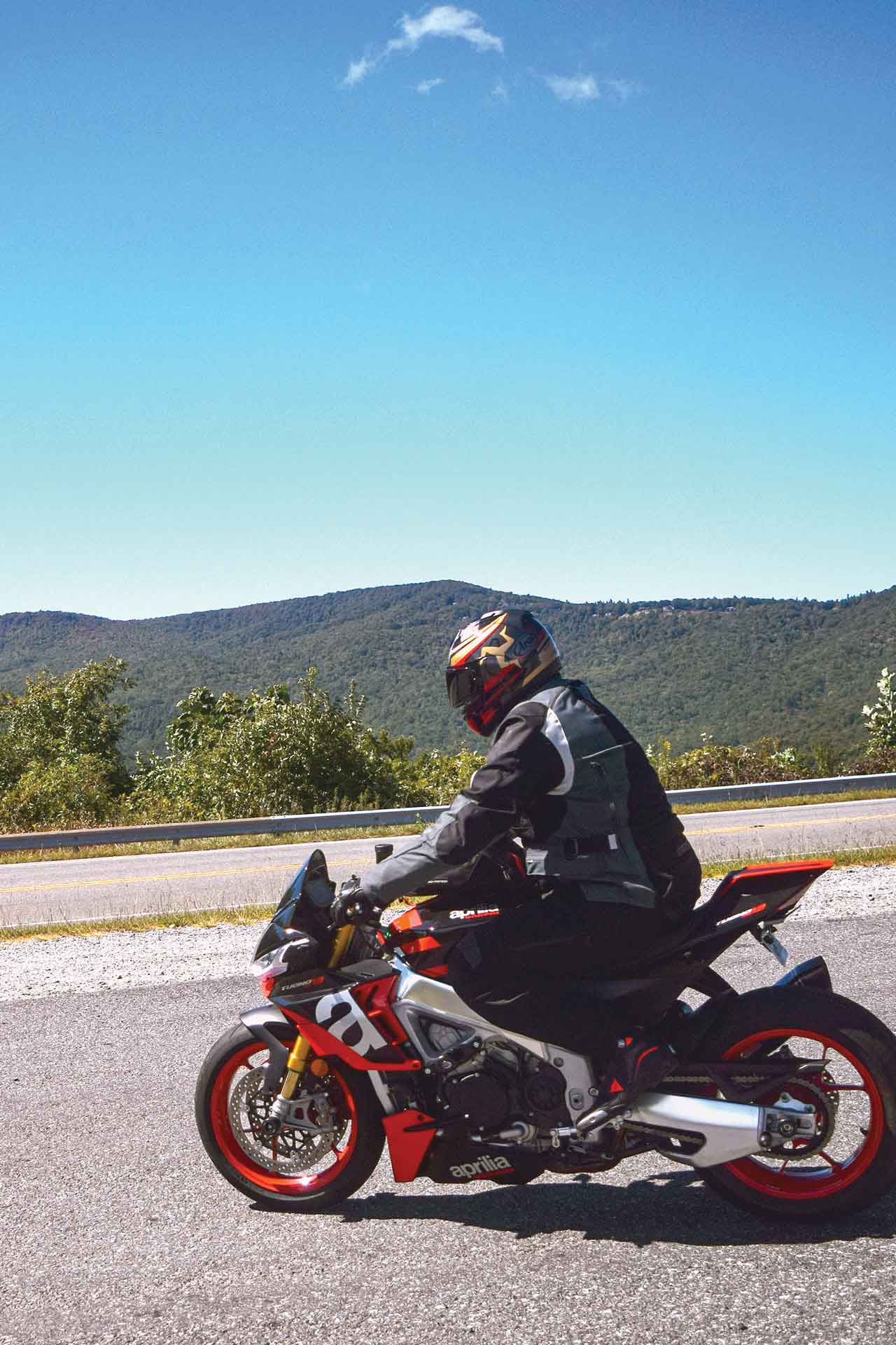 A man riding a red Aprilia motorcycle