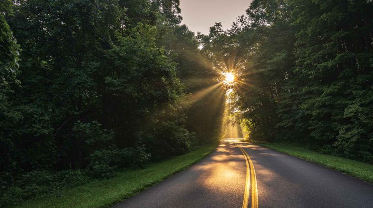 The sun rises over an empty mountain road