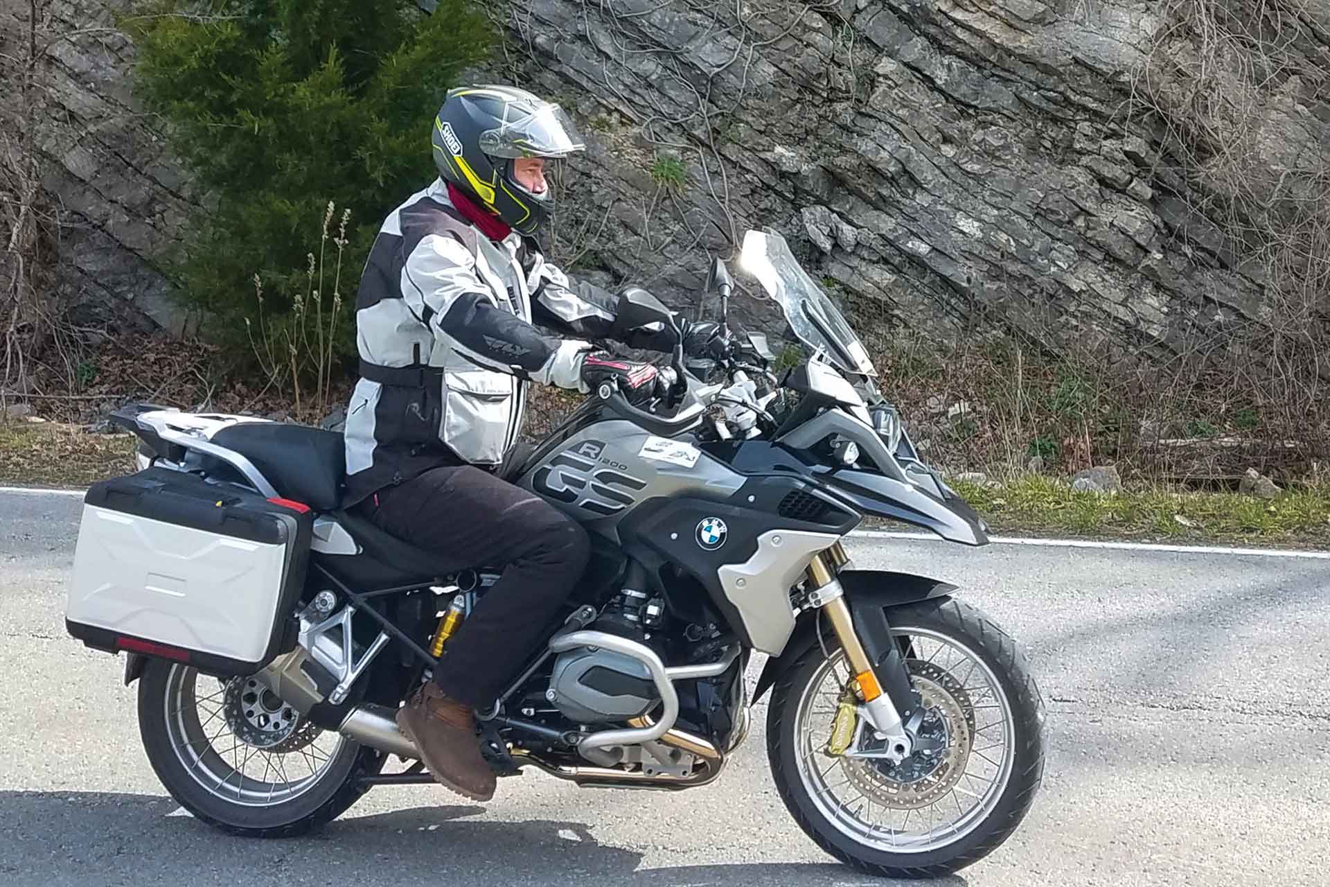 A rider maneuvers a silver BMW motorcycle